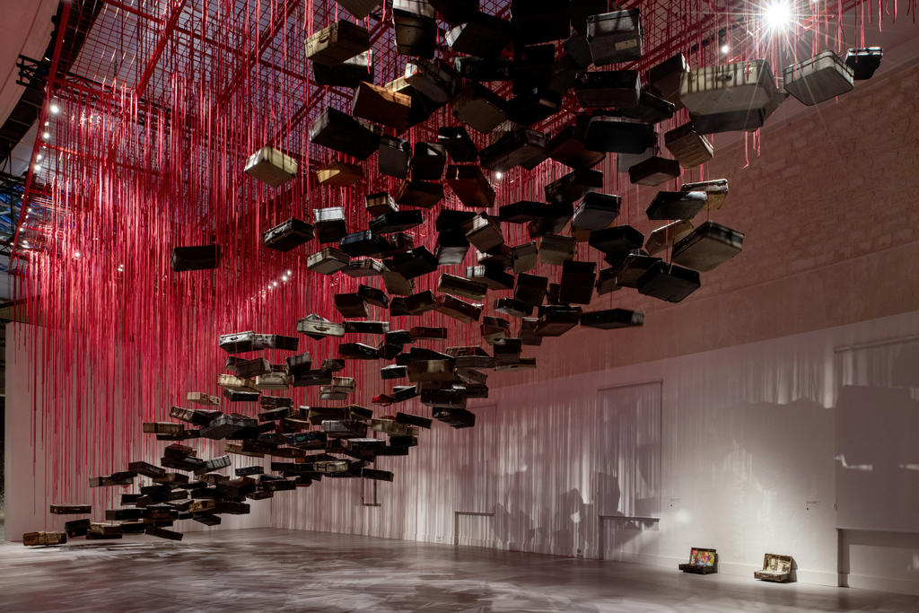 Chiharu Shiota (née en 1972), Accumulation – Searching for the Destination (« Accumulation – En quête de la destination »), 2014/2024. Valises, moteur et corde rouge, dimensions variables. Vue de l’installation :  Chiharu Shiota: The Soul Trembles, Grand Palais, Paris 2024. Scénographie Atelier Jodar.